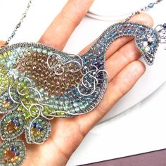 "This necklace was made a showpiece for the annual fair here in San Diego...it it large, gem-encrusted and not for the faint of heart! A fabulous hand-shaped peacock has been formed from various gauges of fine silver wire and meticulous wrapped together. The bird has been filled in with a plethora of varied gemstones: at his head are BLACK DIAMOND chips in his beak, BLACK SPINEL and MOONSTONE around his eye and his neck stretches out, populated with rich blue LONDON BLUE TOPAZ. At the crest of h Whimsical Sterling Silver Jewelry For Party, Peacock Design Jewelry Gift, Peacock Design Jewelry As Gift, Peacock Design Jewelry For Gifts, Silver Peacock Design Jewelry For Party, Wire Wrapped Pendant Jewelry For Parties, Whimsical Pendant Jewelry For Party, Metal Jewelry With Peacock Design For Party, Party Wire Wrapped Pendant Jewelry