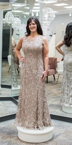 a woman standing in front of a mirror wearing a dress with an intricate design on it