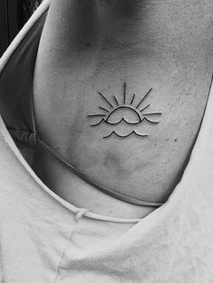 a woman's chest with a small sun tattoo on her left side ribcage