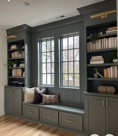 a window seat in the corner of a room with many bookshelves and pillows