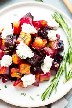 beets, carrots and goat cheese on a white plate with rosemary garnish