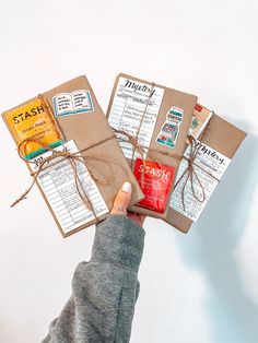 a person holding several pieces of brown paper in their hand with tags attached to them