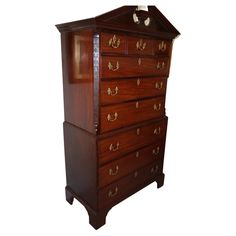 a tall wooden dresser with drawers and knobs on the top shelf, against a white background