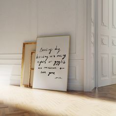 an empty room with two framed pictures on the floor and a quote written in cursive writing