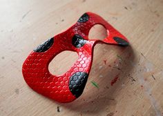 a red and black mask sitting on top of a wooden table