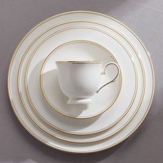 a white cup and saucer with gold rims