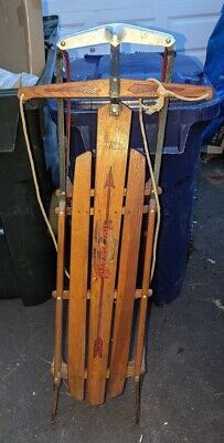 an old wooden sled sitting on top of a floor next to trash cans and bins