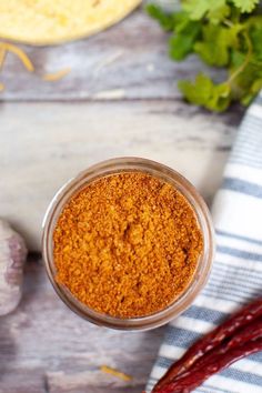 a jar filled with red chili powder next to garlic and cilantro