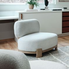 a white chair sitting on top of a wooden floor next to a potted plant