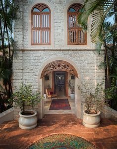 an archway leads into a courtyard with potted plants and two large planters on either side