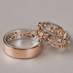 two gold wedding bands with diamonds on them are sitting next to each other in front of a gray background