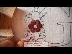 someone is stitching flowers on the side of a piece of fabric that has been embroidered onto