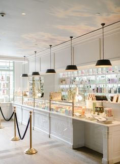 the interior of a cosmetics store with lights and lighting fixtures hanging from the ceiling over the counter