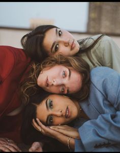 three women laying on top of each other with their arms around one woman's head