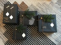 three presents wrapped in black paper with christmas decorations