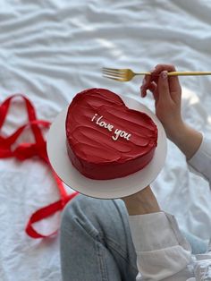 a woman holding a heart shaped cake with the words i love you written on it