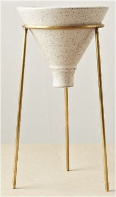 a white vase sitting on top of a wooden stand