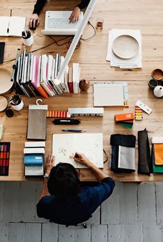 two people sitting at a table with books and laptops