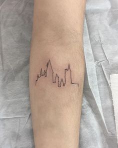 a man with a tattoo on his leg that has three buildings in the shape of mountains