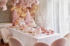 there is a table with pink decorations on it and white chairs around the table in front of them