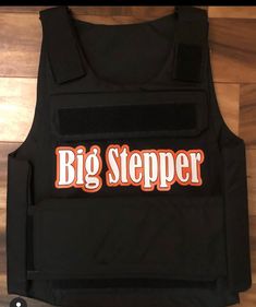 a black vest with the words big steeper on it and an orange stripe across the chest