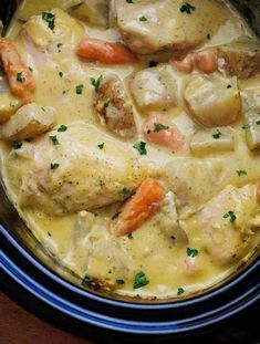 chicken, potatoes and carrots stew in a crockpot on a wooden table