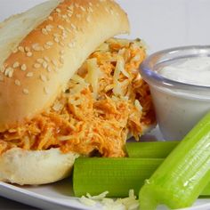 a plate with a sandwich, celery and ranch dip on the side next to it