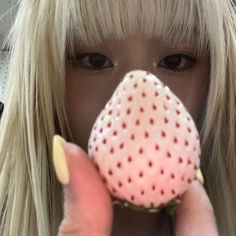 a close up of a person holding a doughnut in front of their face with one hand