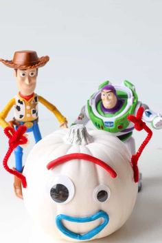 two toy figurines sitting on top of a white pumpkin with woody and buzz lightyear