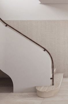 a white stair case next to a wall with a brown hand rail on the side