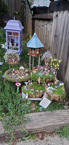 a garden filled with lots of different types of plants and flowers next to a wooden fence