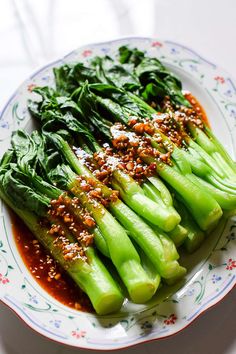 a white plate topped with asparagus covered in sauce and garnished with sesame seeds