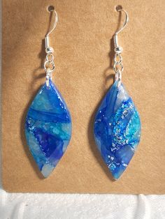 the earrings are made with blue glass and silver metal wire, which is hanging from a hook