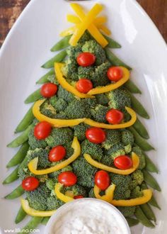 a christmas tree made out of broccoli and peppers on a plate with dip