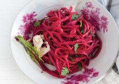 a white bowl filled with red noodles and garnish