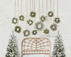 a white brick wall with wreaths hanging on it and a bed in the foreground