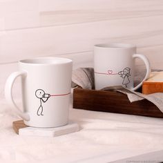 two coffee mugs with stick figures on them