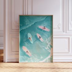 two people on surfboards in the ocean under an art print hanging on a wall