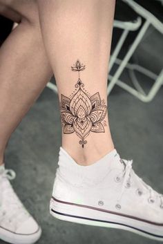 a woman's foot with a flower tattoo on the side of her leg,