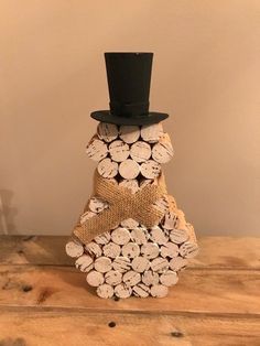 a stack of wine corks with a black top hat on it, sitting on a wooden table