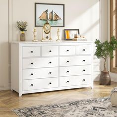 a white dresser with lots of drawers and pictures on it's top, in a living room