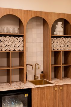 a kitchen with wooden cabinets and shelves filled with towels, soaps and other items