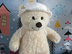 a white teddy bear with a hat on it's head sitting in front of a wall