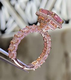 a pink diamond ring sitting on top of a piece of metal