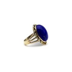 This is part of Chairish’s Fine Jewelry assortment.  A vivid blue lapis cabochon is bezel set into a halo of 22k gold nuggets. The stone is a deep, well-saturated cobalt blue, while the gold nuggets bring richness and texture to the surface of the ring. The effect is stunning, and the two elements compliment each other beautifully. The 14k gold band splits into three, adding a hint of drama and elegantly framing the lapis centrepiece. A bold cocktail ring, true blue!  This type of nugget work ar Gold Dome Cabochon Ring In 14k Gold, Classic Blue Gemstone Cabochons, Gold Domed Gemstone Cabochons, Blue Domed Jewelry With Polished Finish, Domed Gold Gemstone Cabochons, Blue Cabochon Sapphire Ring In 14k Gold, Blue Domed Gemstone Ring, Gold Lapis Lazuli Cabochon Jewelry, Gold Lapis Lazuli Jewelry With Cabochon