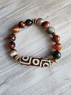 a brown and white beaded bracelet sitting on top of a wooden table