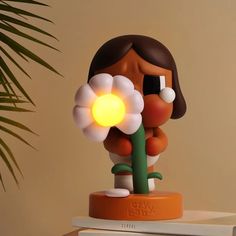 a little figurine holding a flower on top of a table