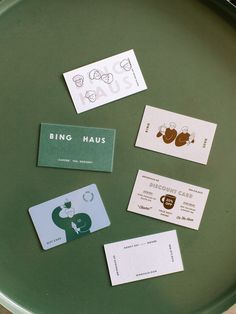 some business cards are laying on a green tray with white and black stickers that read bing haus