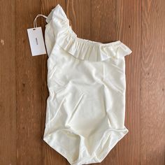 Mikoh Mini Swimwear Ray One Piece One Shoulder Swimsuit Girls Xl Nwt Off White / Bone Color One Shoulder Style With Ruffle Detail Will Be Shipped In Mikoh Clear Plastic Zip Pouch Solid Fitted Bodysuit For Playwear, Fitted Solid Color Bodysuit For Playwear, White Stretch Cotton Onesie, Spring Beachwear Tops For Play, Cream Fitted Bodysuit For Loungewear, White Cotton Stretch Onesie, White Stretch One-piece Leotard, White Stretch Onesie For Loungewear, White Stretch Bodysuit For Loungewear