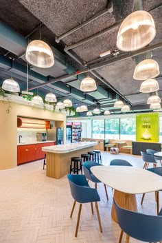 an empty cafeteria with blue chairs and white counter tops is pictured in this image, there are several lights hanging from the ceiling